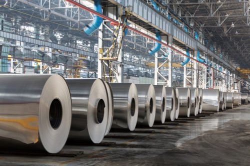 Row of rolls of aluminum lie in production shop of plant.